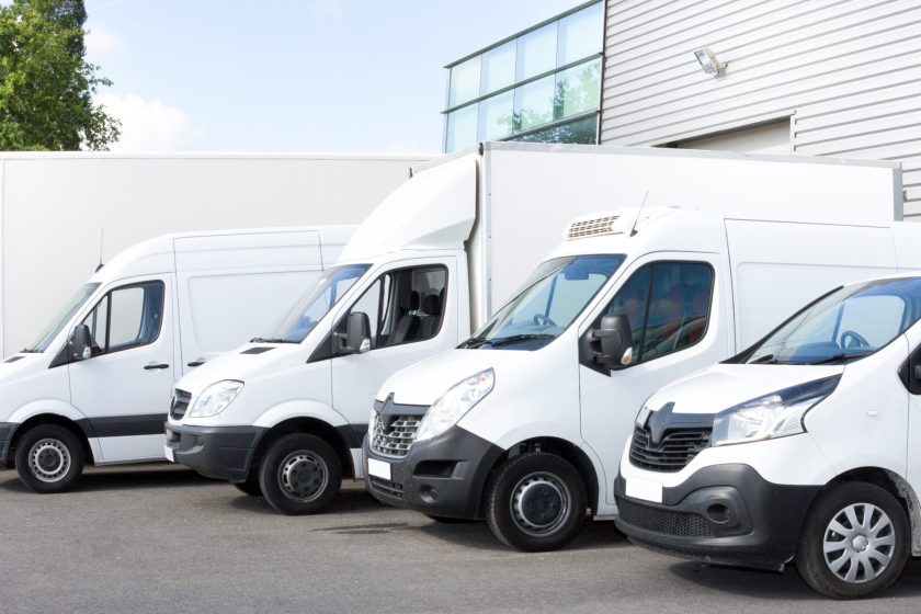 Several cars vans trucks parked in parking lot for rent or delivery