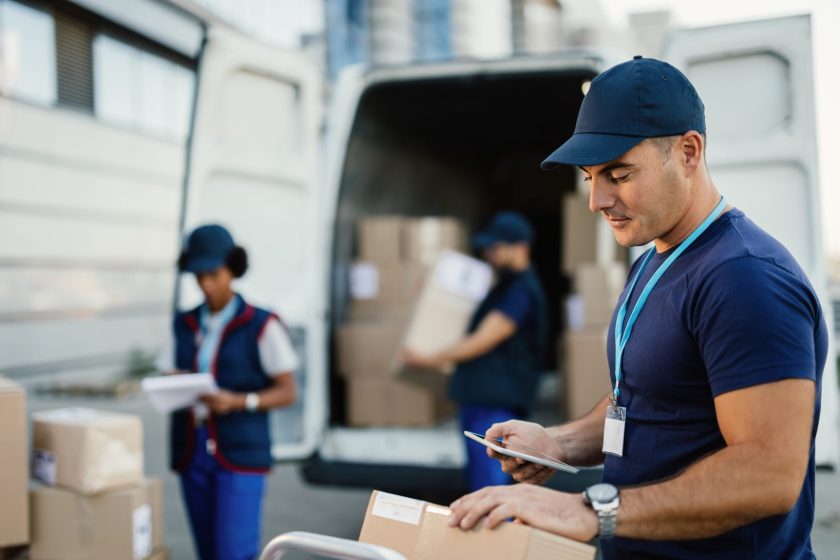 Young worker using touchpad while making a delivery in the city.