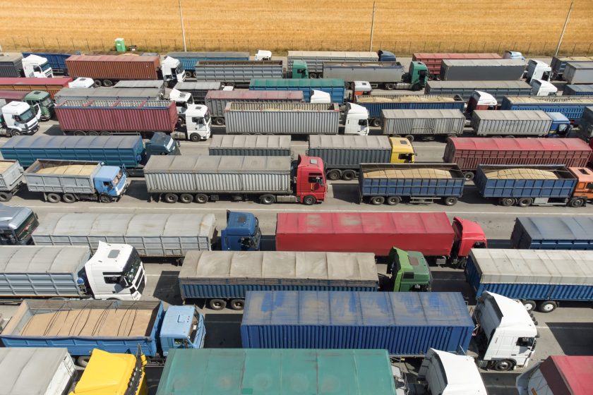 Trucks in line to unload grain at the port. Aerial view of many trucks with trailers.