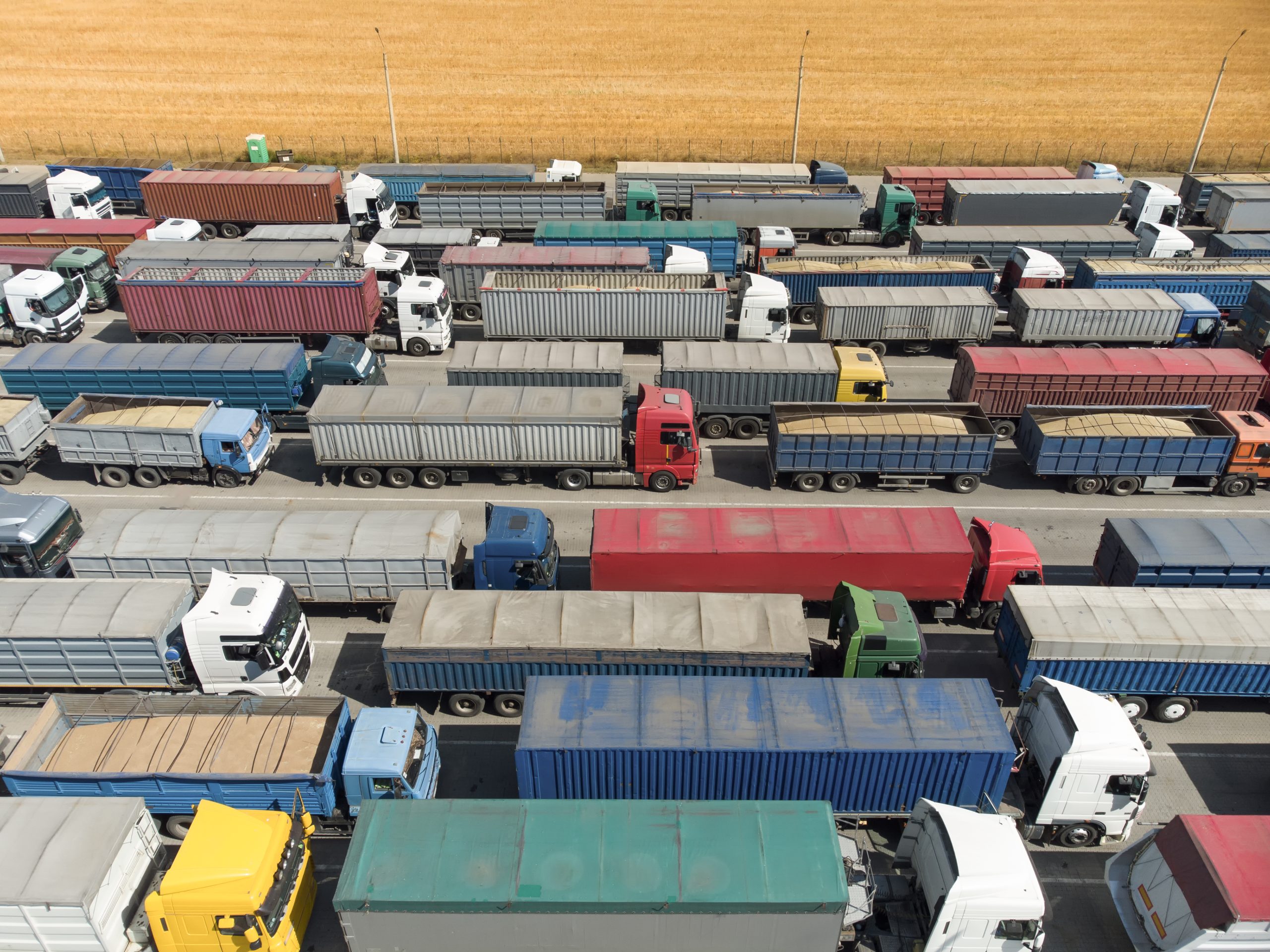 Trucks in line to unload grain at the port. Aerial view of many trucks with trailers.